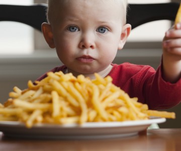 Toddler eating a large plate of French fries