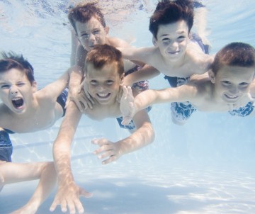 Friends Swimming Underwater in Backyard Pool --- Image by © Royalty-Free/Corbis
